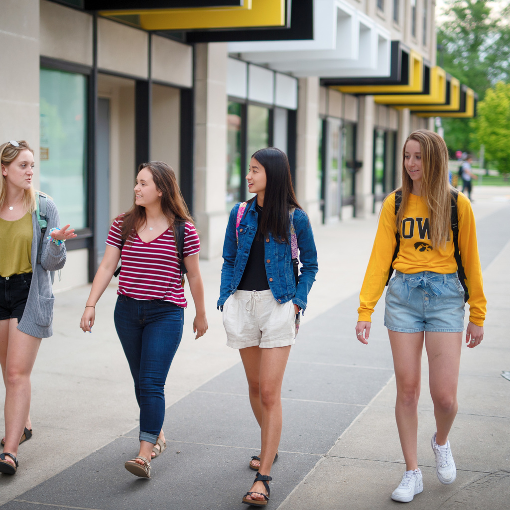 Four students walking down a sidewalk