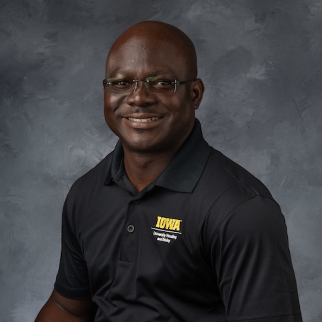 portrait of a Black man wearing glasses and a black shirt with Iowa logo
