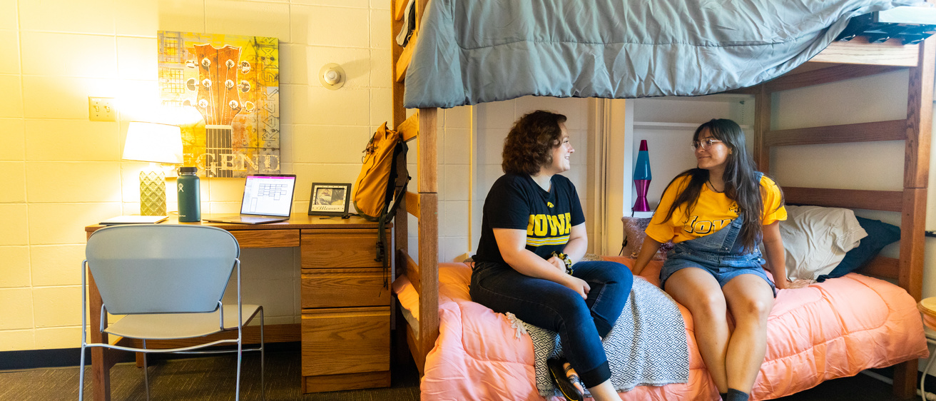 Two student sitting on a bunk bed and talking with one another