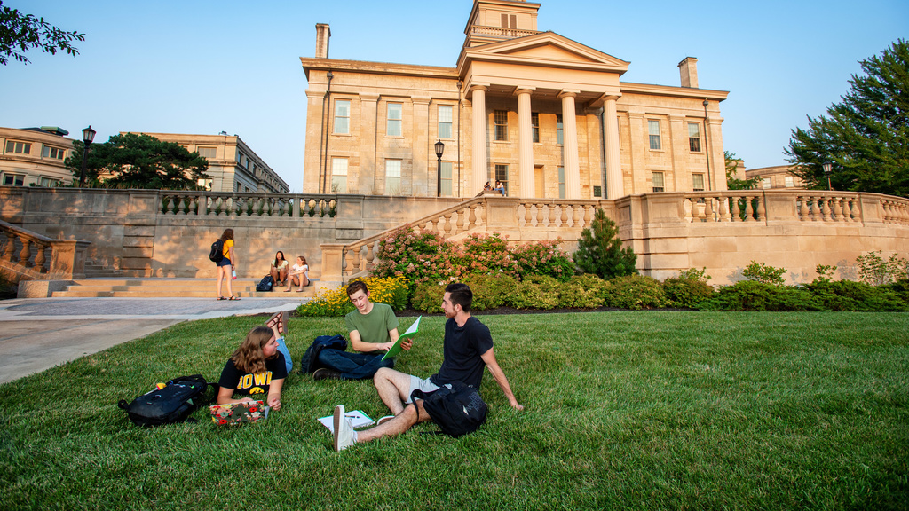Four students sitting on the grass and talking
