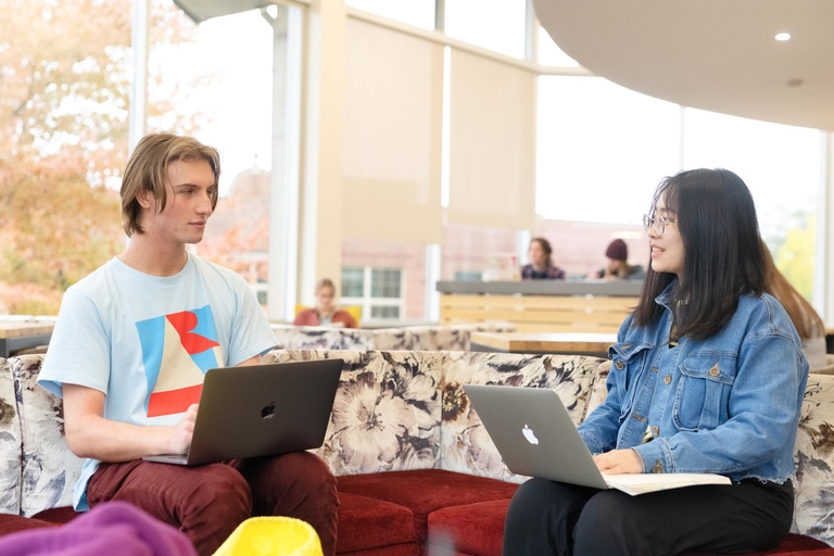 Two students sitting on a couch in a study lounge and talking