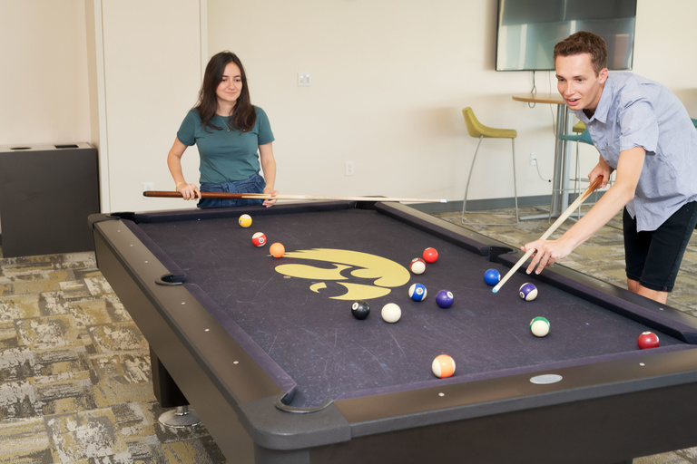 Two students playing a game of pool