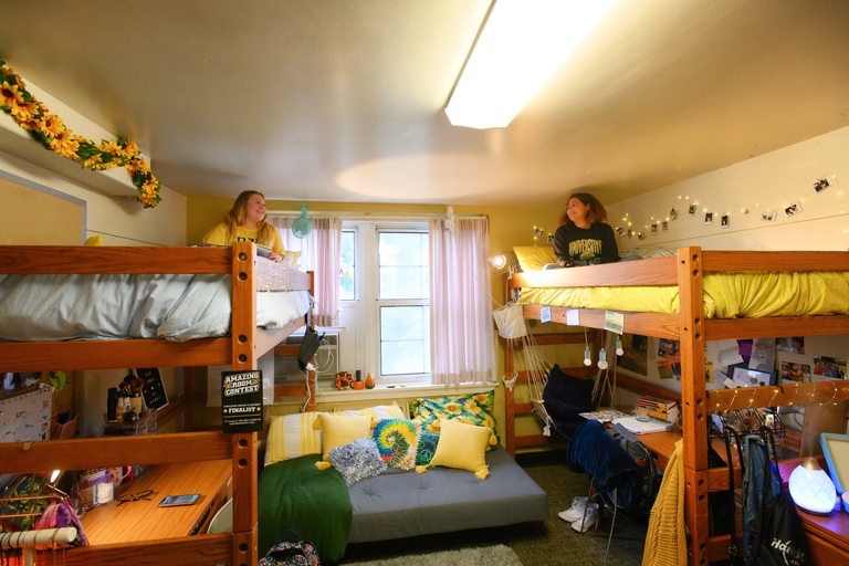Student sitting in lofted beds and talking with one another