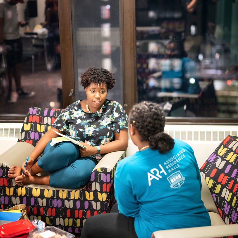 Student talking with another student on a couch