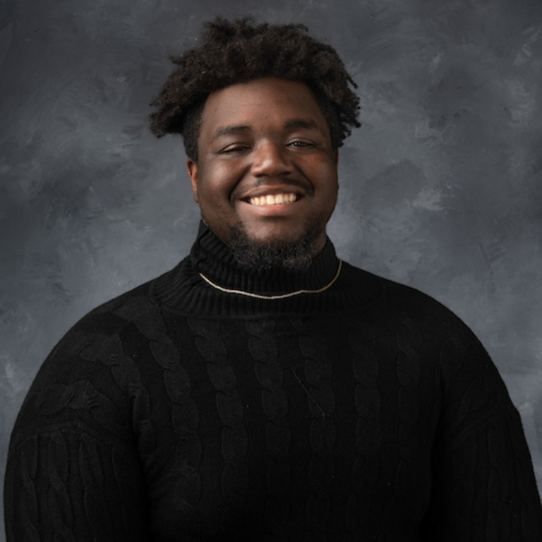 Portrait of a Black man wearing a black turtleneck and chain necklace