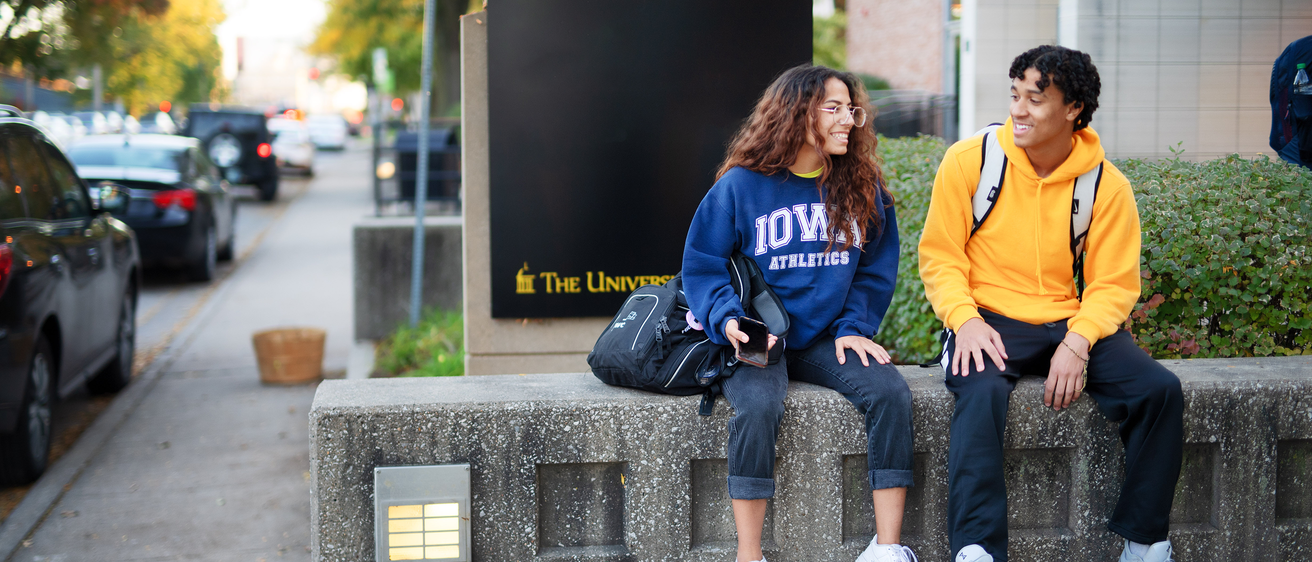 Two students sitting near a residence hall