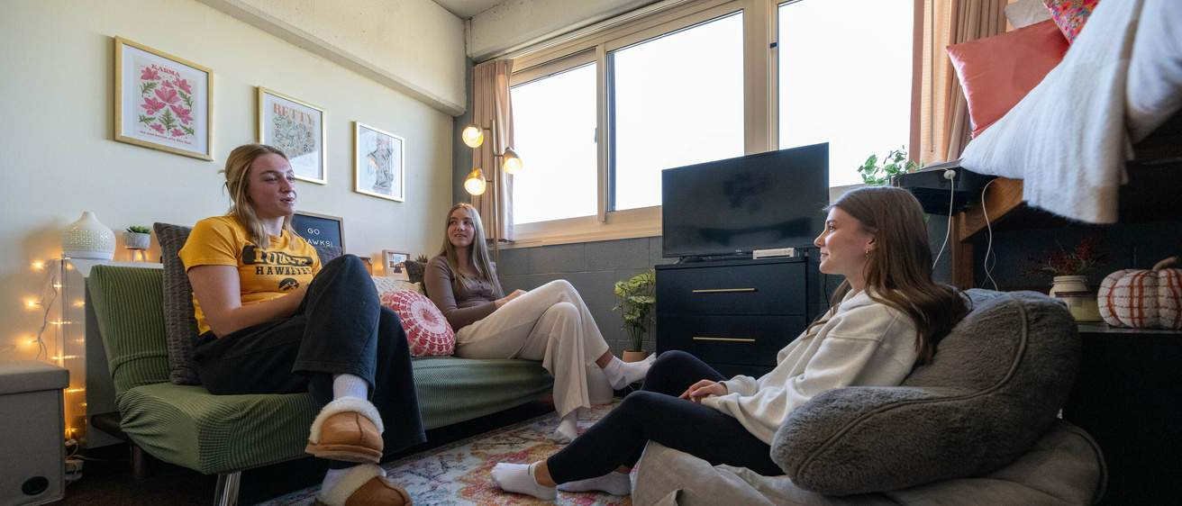 two residents in mayflower sit on a green futon, opposite another woman sitting on a gray beanbag chair
