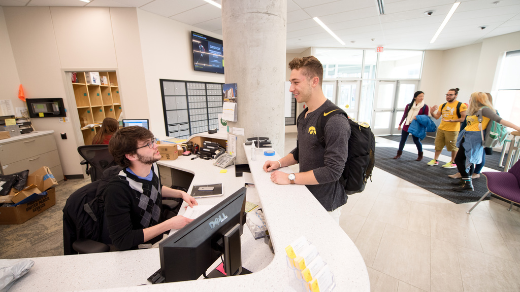 A student talking with another student a residence hall front desk