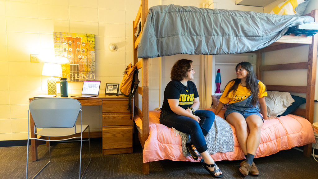 Two student sitting on a bunk bed and talking with one another